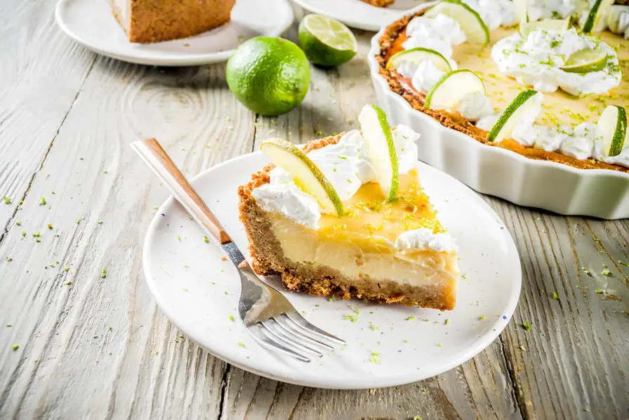 A piece of key lime pie sitting on a dish with a fork.