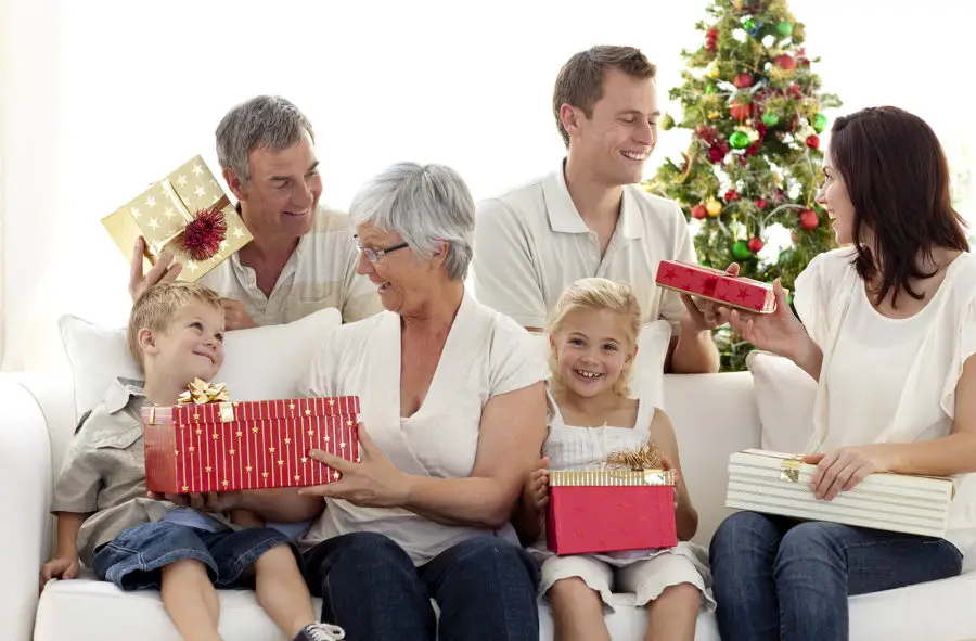 A family sitting on a couch exchanging presents.